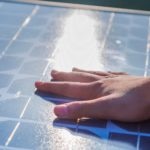Human hand touching a solar panel